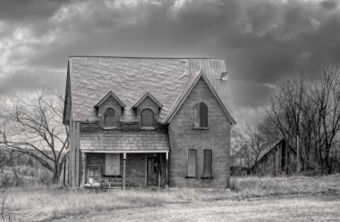 Eski siyah beyaz terk edilmiş ürkütücü görünümlü bir ev kışın Kanada kırsalındaki bir çiftlik bahçesinde