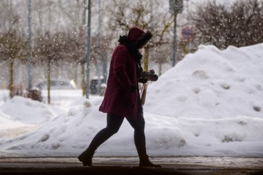 RIGA, LATVIA. 5 Şubat 2021. Seçici odak fotoğrafı. Kar yağarken sokakta yürüyen biri..