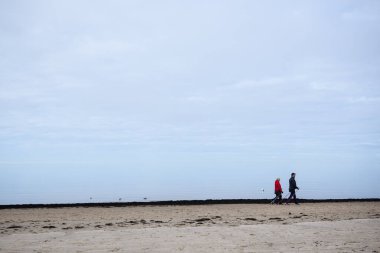 JURMALA, LATVIA. 23 Mart 2021. Seçici odak fotoğrafı. Son sınıflardan birkaçı deniz kenarında sırıklarla yürüyor. Huzurlu ve sisli deniz.