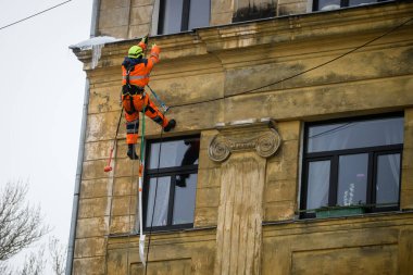 RIGA, LATVIA. 30 Aralık 2021. Tırmanışçılar çatıdan buz ve kar temizliyor..