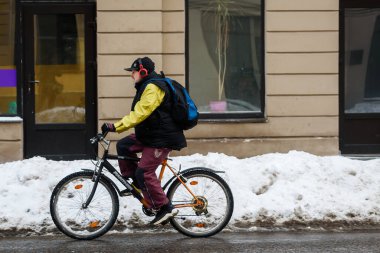 RIGA, LATVIA. 2 Şubat 2021. Kaygan yolda bisiklete binen bir adam.