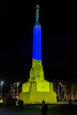 RIGA, LATVIA. 25 Şubat 2022. Ukrayna bayrak renklerinde Özgürlük Anıtı parladı.