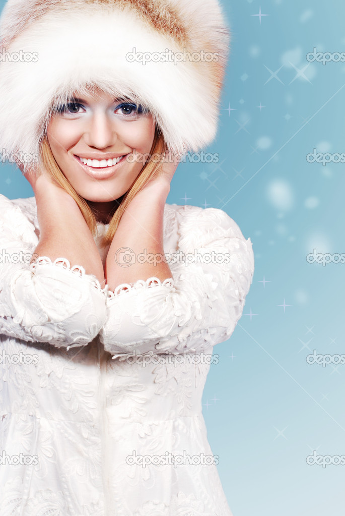 Beautiful woman in fur hat on the shining winter background