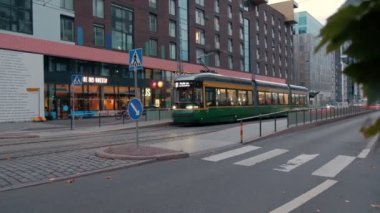 Helsinki, Finlandiya - 3 Ekim 2021: Modern Tram Jatkasaari mahallesindeki yaya köprüsünün altından geçiyor. Modern Avrupa İskandinav Mimarisi.