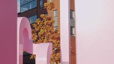 Modern İskandinav mimarisi. Konut binasının ön cephesindeki tuğlalar. Helsinki, Finlandiya 'nın Kalasatama mahallesinde. Önplanda sonbahar sarı ağacı ve pembe metal heykel