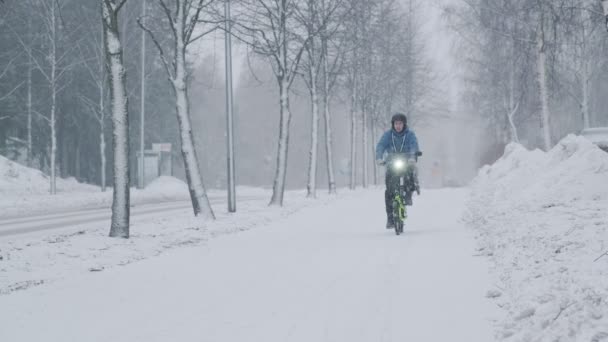 A kerékpáros mozog az utcán a hóvihar alatt. — Stock videók