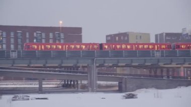 Metro treni kar fırtınası sırasında köprüde hareket ediyor.