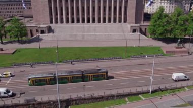 Helsinki, Finlandiya - 9 Haziran 2022: ForCity Smart Artic Helsinki tramvayı Finlandiya parlamentosundan geçiyor. Hava görüntüsü. Yavaş çekim, 0.5 hız