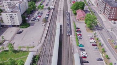 Espoo, Finlandiya - 6 Haziran 2022: Banliyö treninin hava görüntüsü. Tren istasyona varmak üzere. Yaz güneşli bir gün. Yavaş çekim, 0.5 hız.