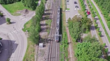Espoo, Finlandiya - 6 Haziran 2022: Demiryolu ile hareket eden banliyö treninin hava görüntüsü. Yaz güneşli bir gün. Yavaş çekim, 0.5 hız.
