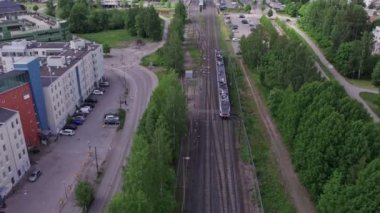 Espoo, Finlandiya - 6 Haziran 2022: Banliyö treninin hava görüntüsü. Tren istasyona varmak üzere. Yaz güneşli bir gün. Yavaş çekim, 0.5 hız.