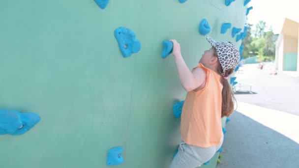 Little Girl Climbs Green Climbing Wall Outdoor Playground Slow Motion — Stockvideo