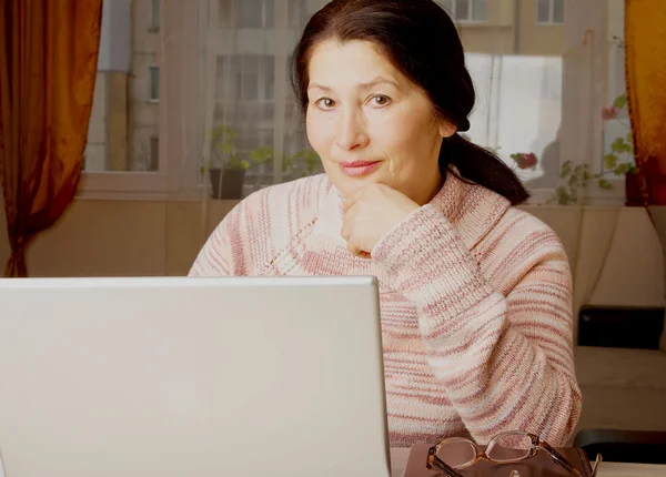 Seniorkvinne med bærbar pc, avslappende på sofaen . – stockfoto