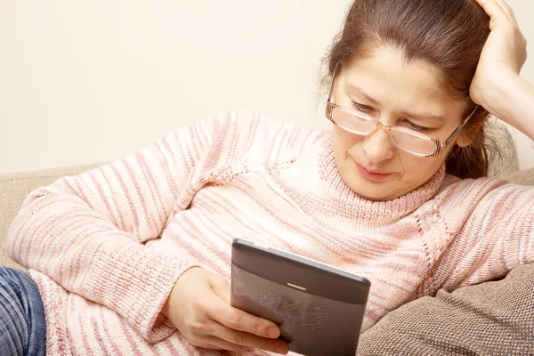 Senior bonita mujer usando tableta PC mientras se apoya en el sofá — Foto de Stock