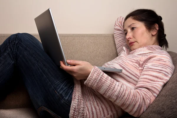 Idősebb nő, laptop, pihentető a kanapén. — Stock Fotó