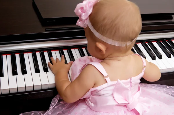 Beautiful baby girl plays piano — Stock Photo, Image