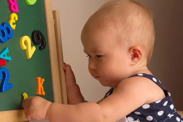 Funny baby flicka som leker med bokstäver — Stockfoto