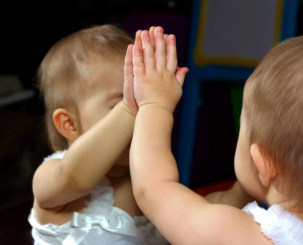 Baby op zoek een spiegel met zichzelf reflectie — Stockfoto