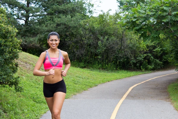 Smiling young woman running for fitness — Stock Photo, Image