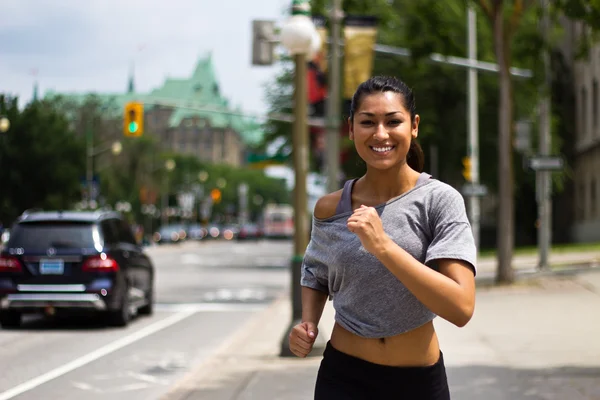 Ajuste mujer joven corriendo en una calle de la ciudad ocupada — Foto de Stock