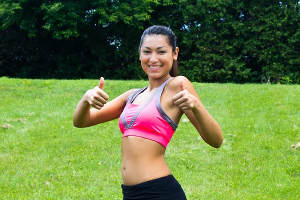 Thumbs up for a fit young woman in the park — Stock Photo, Image