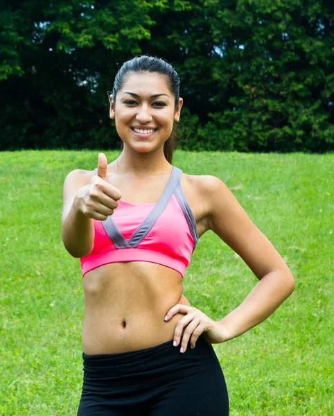 Thumbs up voor een fit jonge vrouw in het park — Stockfoto