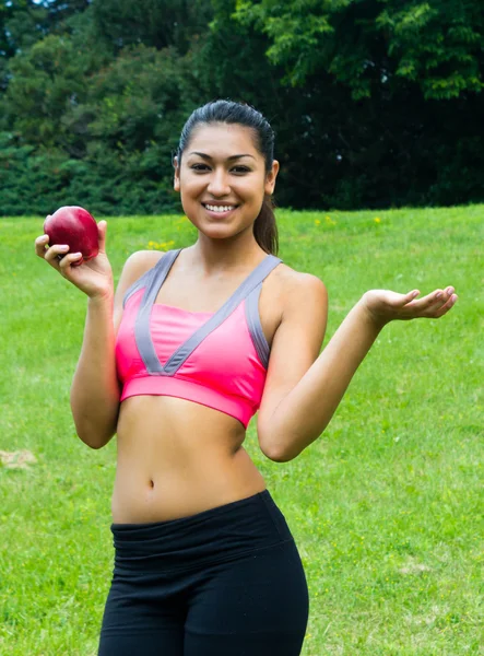 Ajuste mujer joven con una manzana en el parque — Foto de Stock