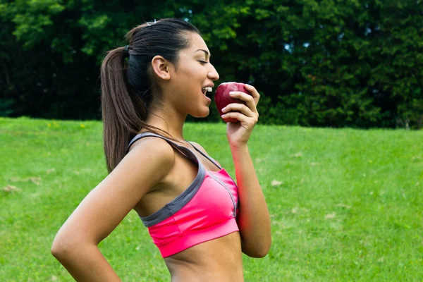 Jonge vrouw eten een appel passen — Stockfoto