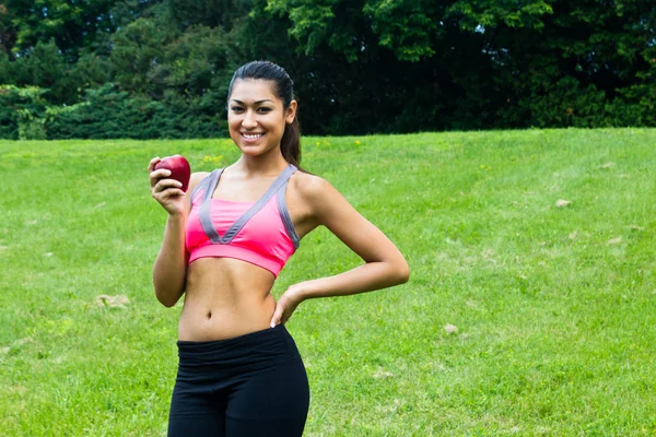 Fitte junge Frau mit einem Apfel im Park — Stockfoto