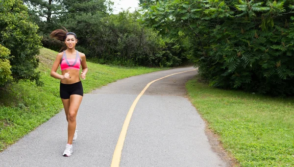 Smiling young woman running for fitness — Stock Photo, Image