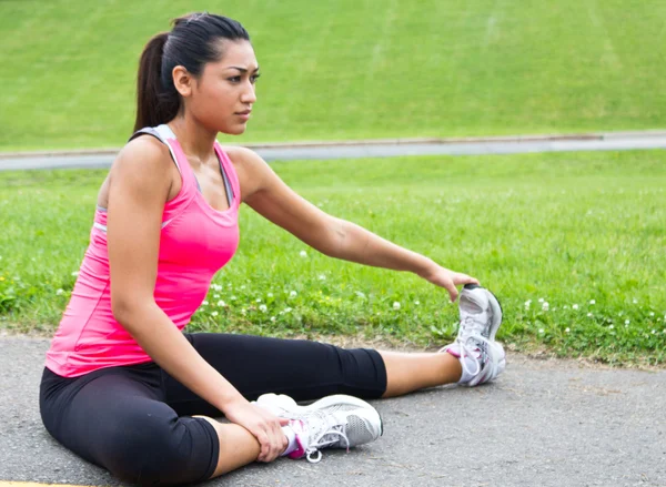Young woman stretches before running — Stock Photo, Image