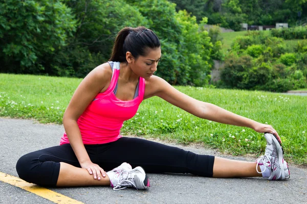 Young woman stretches before running — Stock Photo, Image