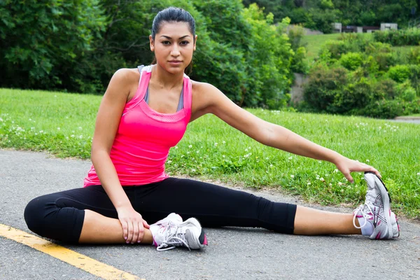 Jovem mulher se estende antes de correr — Fotografia de Stock