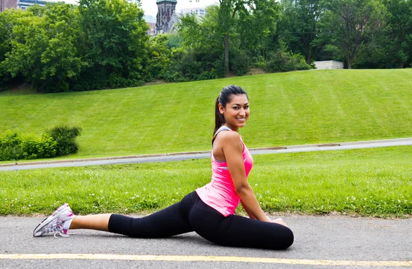 Jonge vrouw die zich uitstrekt voordat een jog — Stockfoto