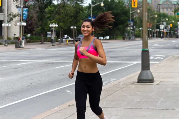 Ajuste mujer joven corriendo en una calle de la ciudad ocupada —  Fotos de Stock