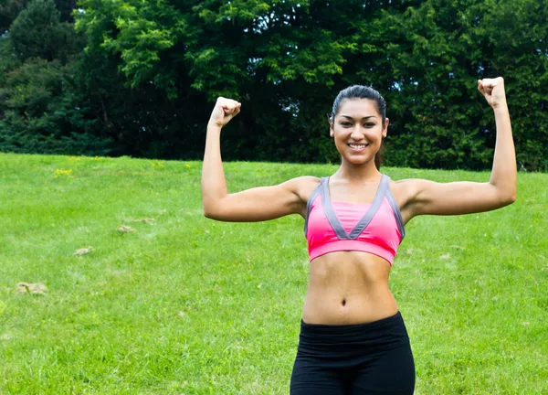 Joven en forma mujer flexiona sus músculos —  Fotos de Stock