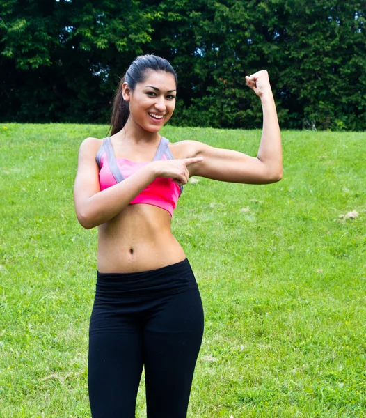 Young fit woman flexes her muscles — Stock Photo, Image