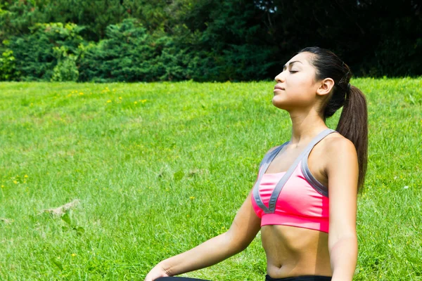 Young fit woman practices yoga in the park to meditate and relax — Stock Photo, Image