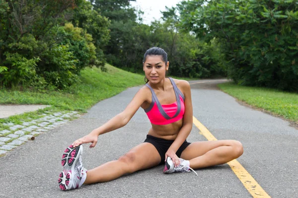Mujer joven se estira antes de correr — Foto de Stock