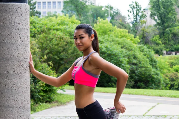 Jovem mulher se estende antes de correr — Fotografia de Stock