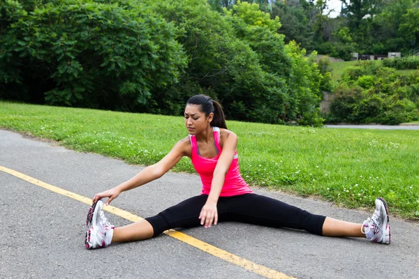 Mujer joven estirándose antes de una carrera — Foto de Stock