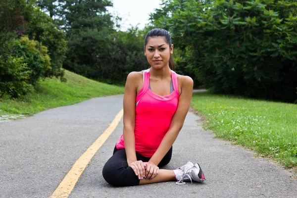 Jonge vrouw die zich uitstrekt voordat een jog — Stockfoto