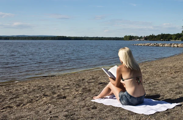 Kumsalda kitap okuyan bir kadın. — Stok fotoğraf