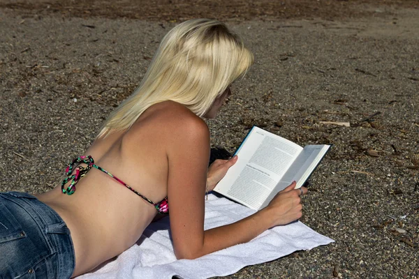 Vrouw die een boek leest op het strand — Stockfoto