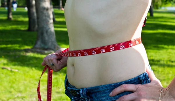 Fit young woman with measuring tape aroung waist — Stock Photo, Image
