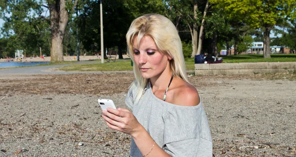 Mujer joven en la playa usando un teléfono inteligente — Foto de Stock