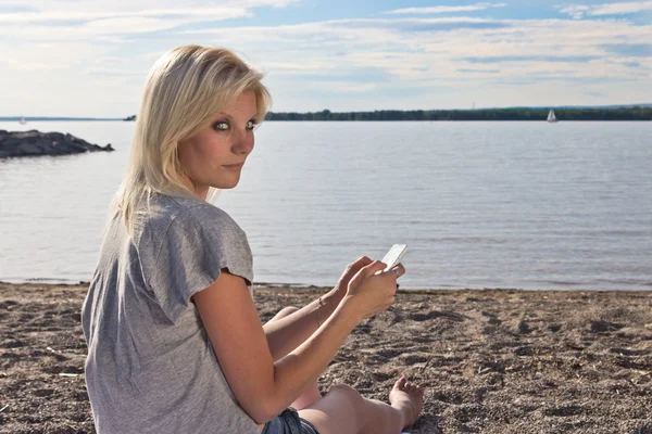 Young woman on the beach using a smart phone — Stock Photo, Image