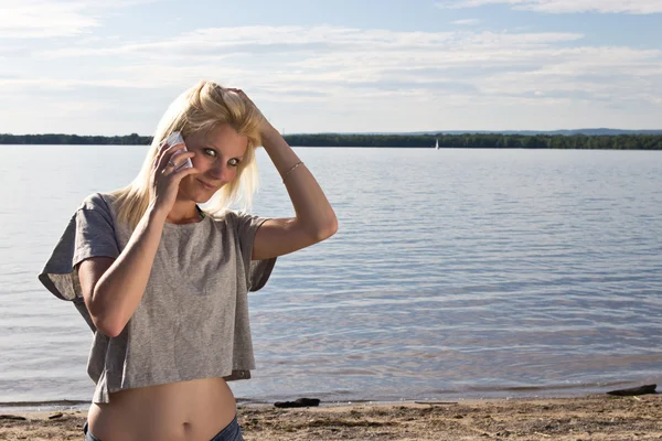 Молода жінка розмовляє по смартфону на пляжі — стокове фото