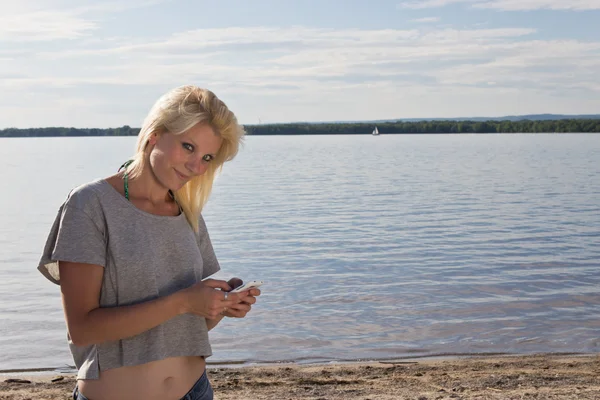 Jonge vrouw op het strand met behulp van een slimme telefoon — Stockfoto