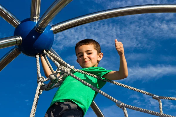 Bambino che gioca sulla struttura del parco — Foto Stock